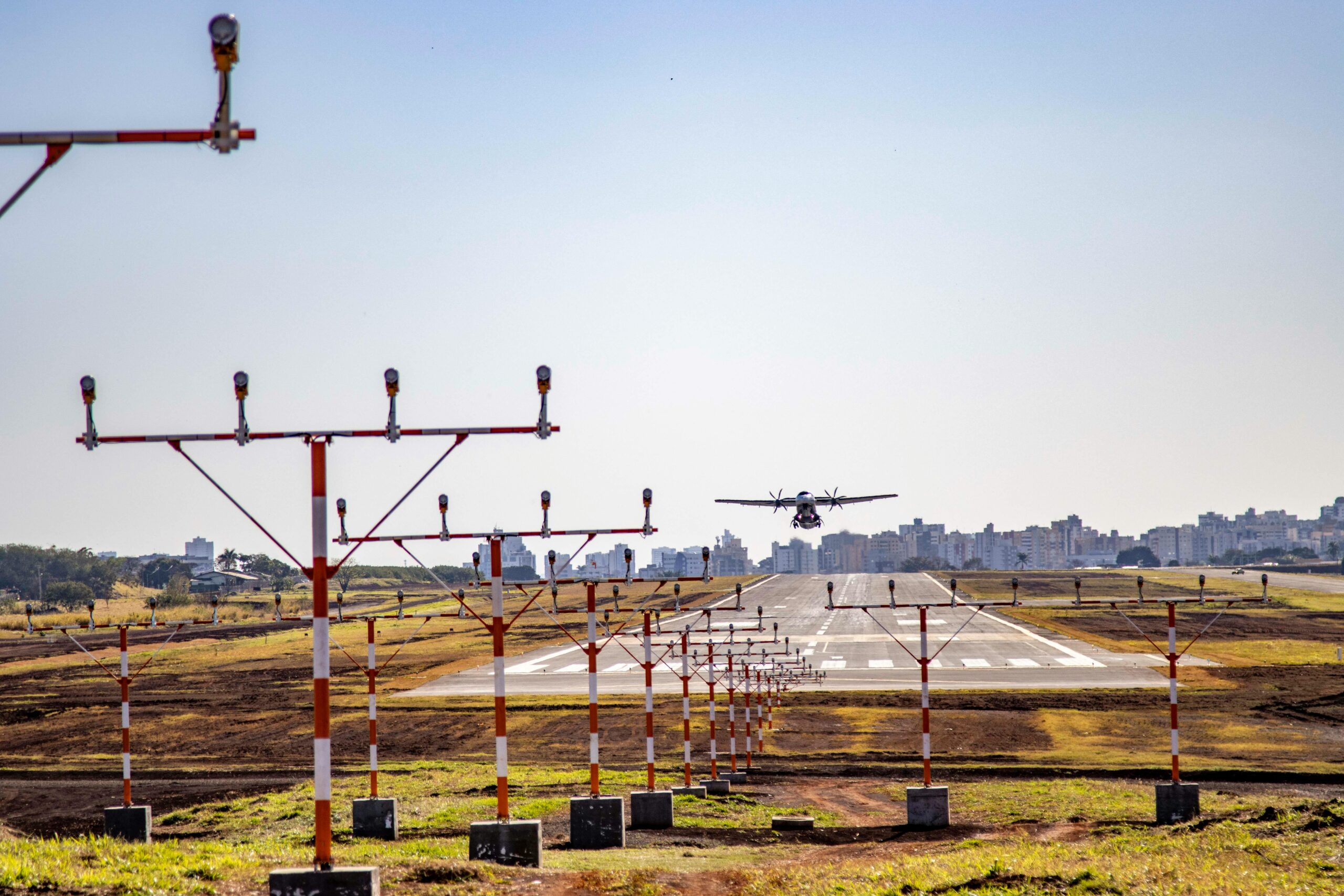 Home An airplane lands on the runway at Londrina Airport, Brazil, with cityscape in background.